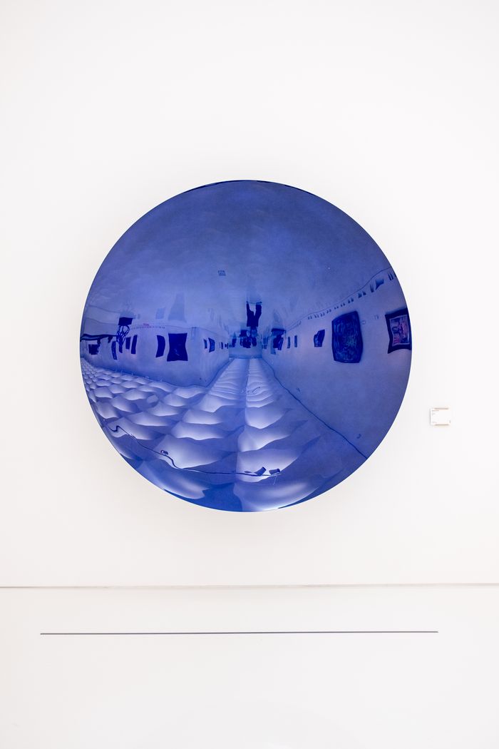 About Abstract blue circular art piece on white wall in contemporary museum setting.