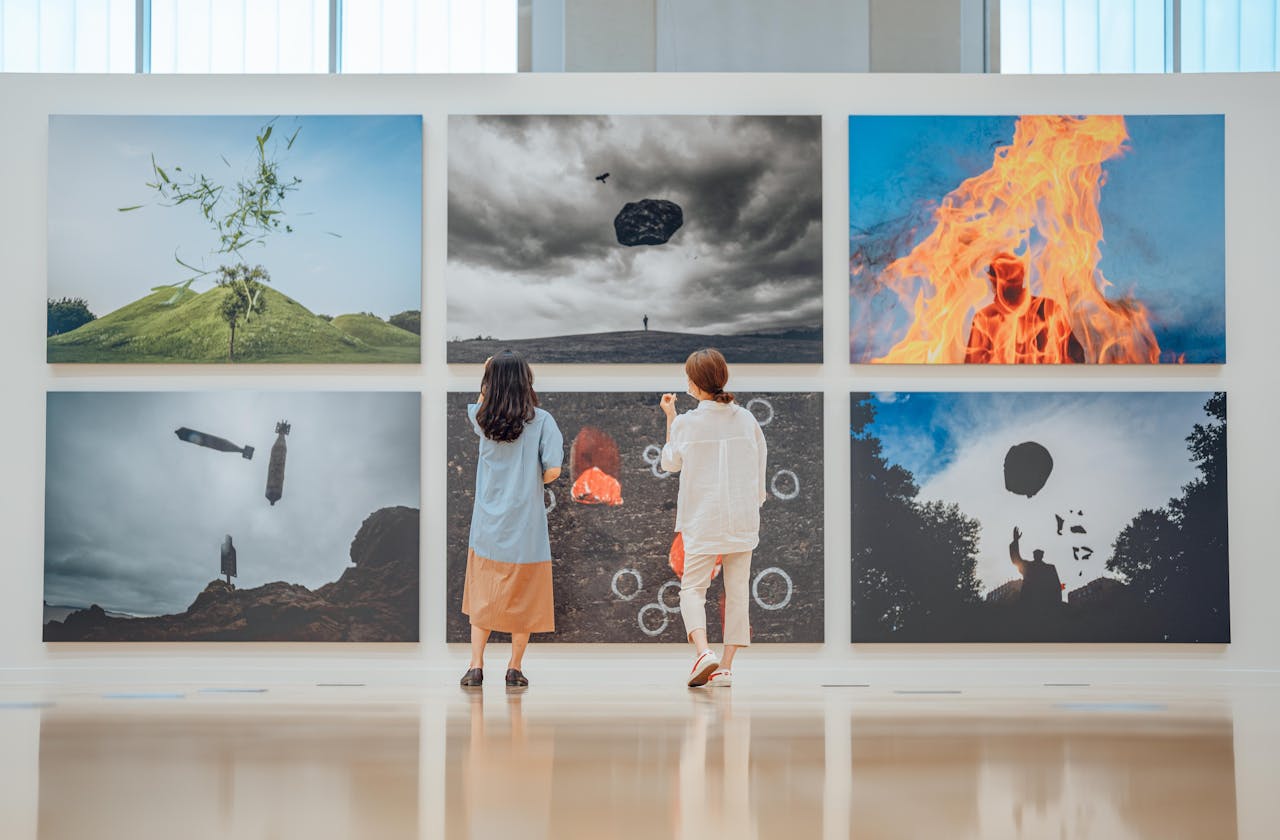 Home Two people observe various artworks in a modern art gallery setting.