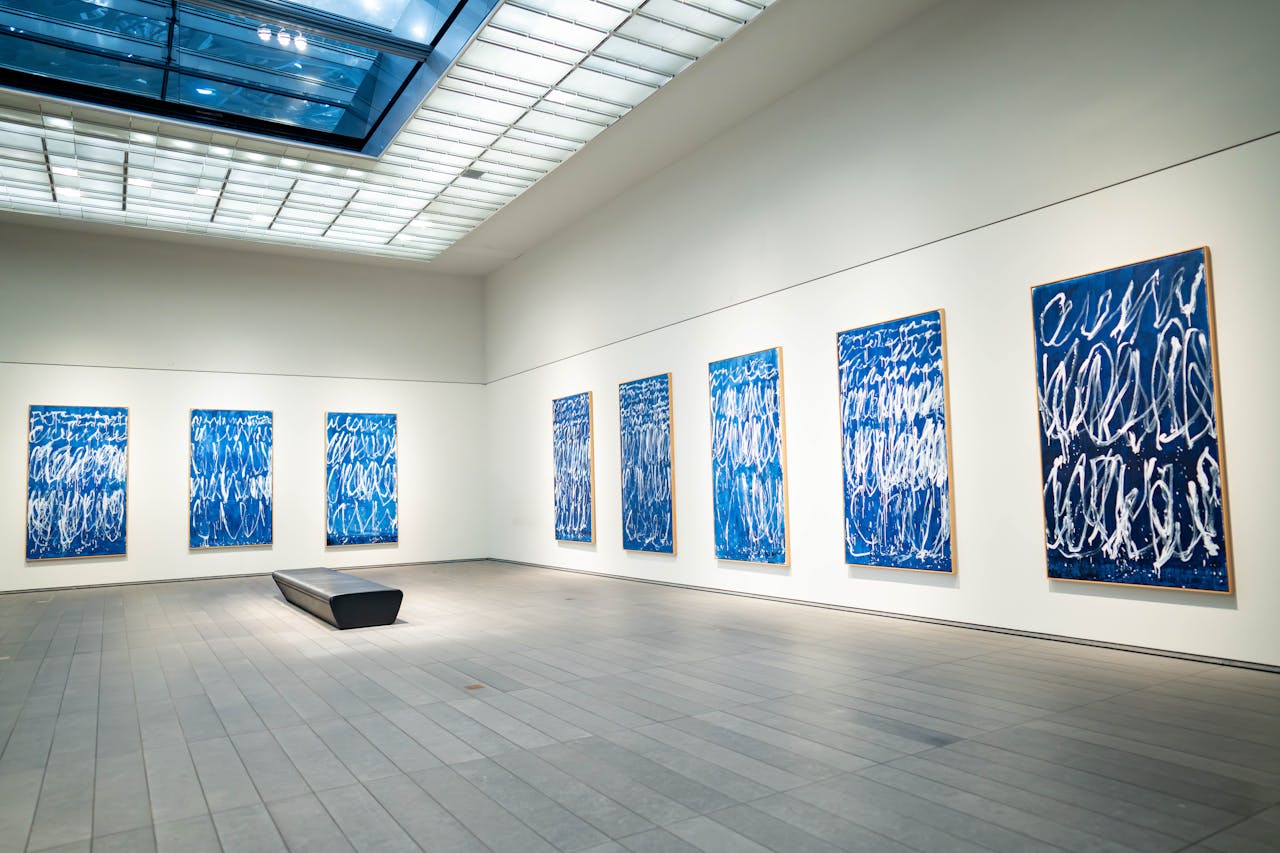 Home Spacious modern art gallery featuring a collection of blue abstract paintings on display.