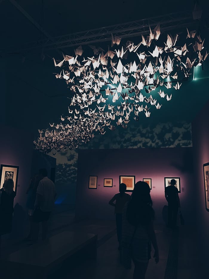 Elegant origami display in a dimly lit Singapore art gallery with a crowd.