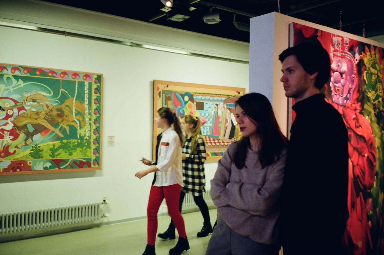 Portfolio Visitors engaged with vibrant art pieces in a St. Petersburg gallery, showcasing modern creativity.